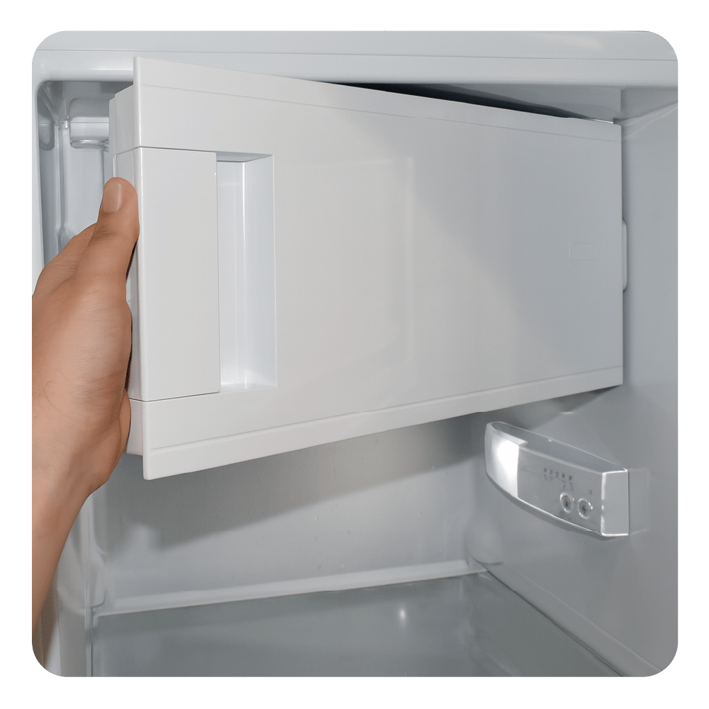 Eine Hand zieht eine weiße Schublade aus einem Kühlschrank.
