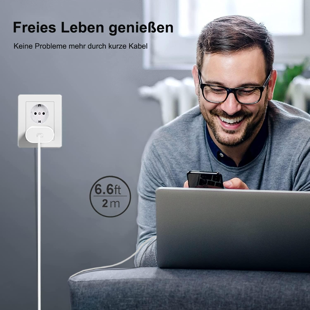 Mann lacht, schaut auf Handy. Stecker und Kabel neben Steckdose. 6.6ft/2m.