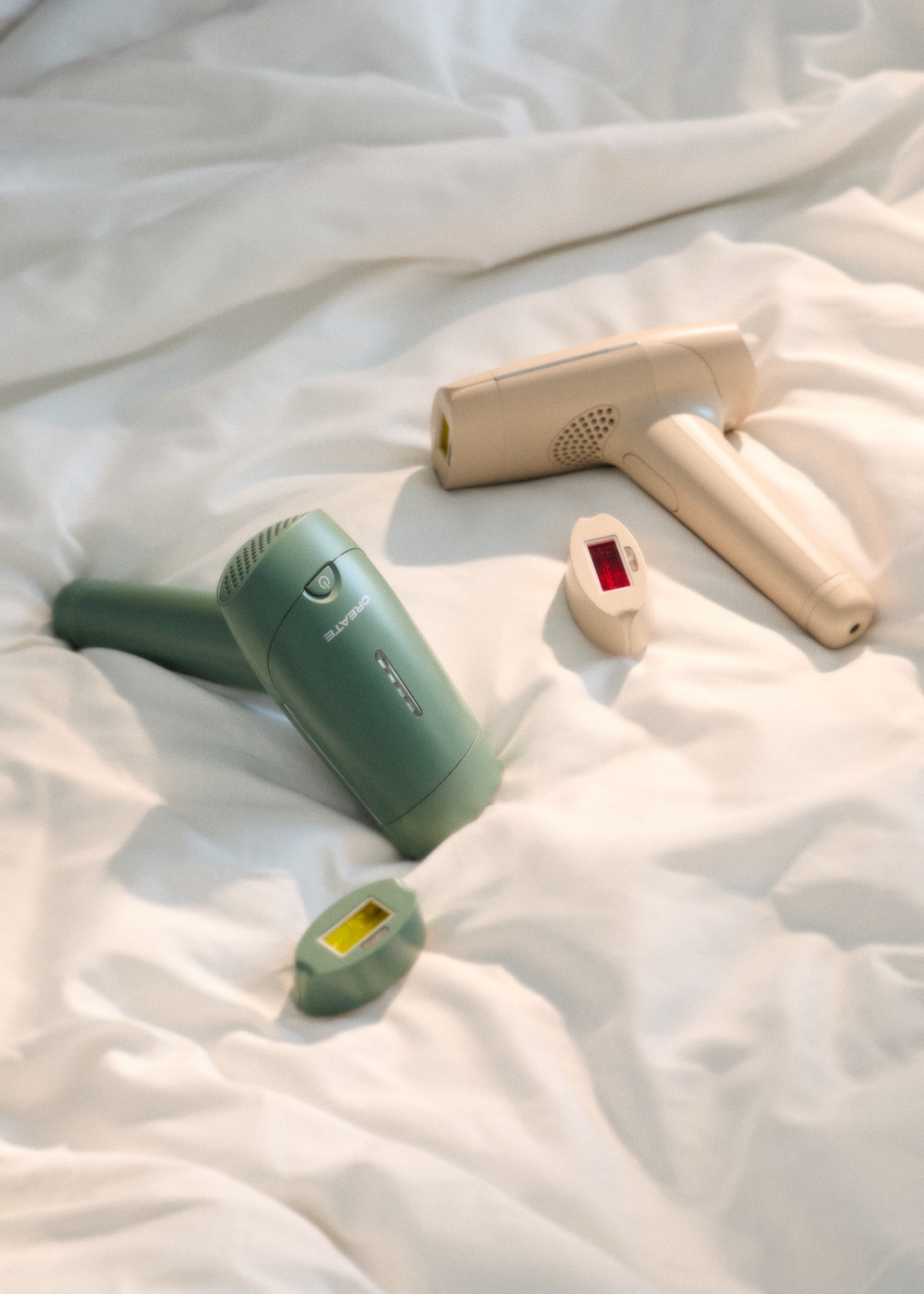 Dos depiladoras IPL y dos accesorios sobre ropa de cama blanca.