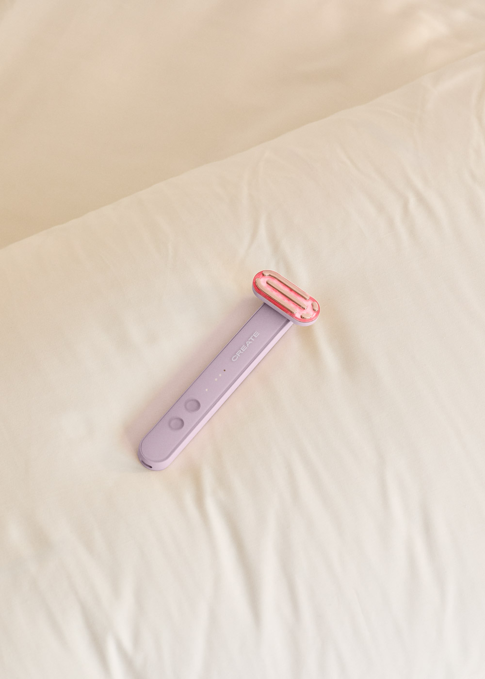 Un dispositivo morado con cabeza rosa descansa sobre una superficie arrugada color crema.