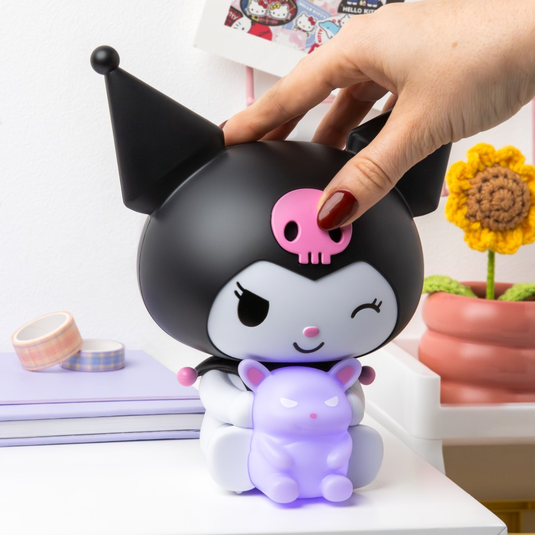 Ręka dotyka czarnej figurki Kuromi z różową czaszką. Trzyma małego fioletowego króliczka.