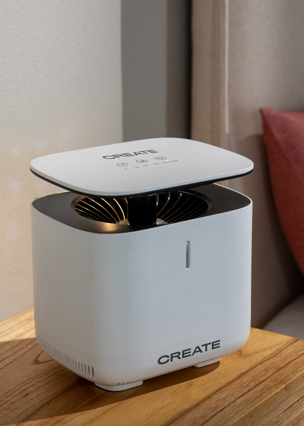 Un purificador de aire blanco con ventilador y logo 'CREATE' en mesa.