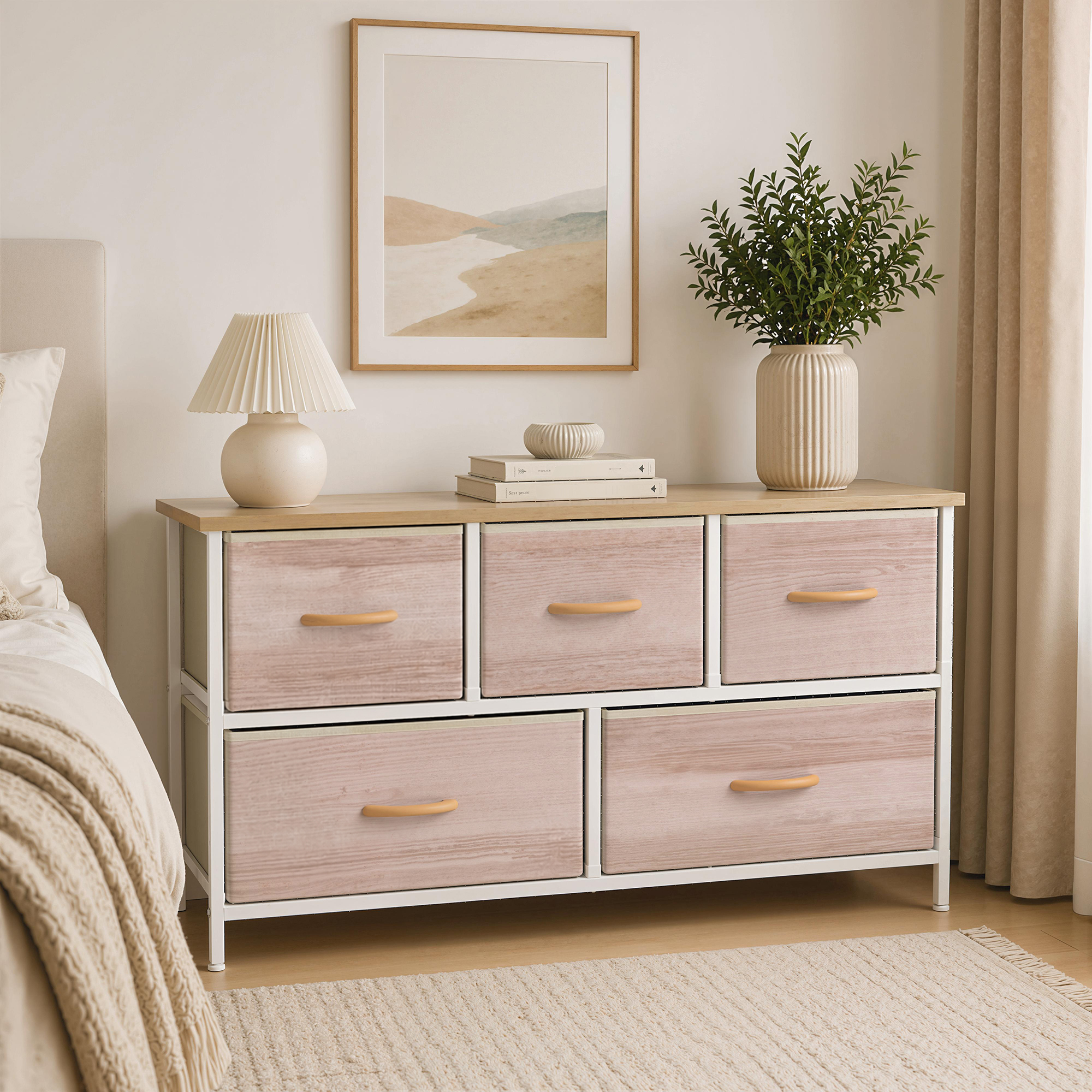 Una escena de dormitorio con una cómoda, cama, lámpara y cuadro en la pared.