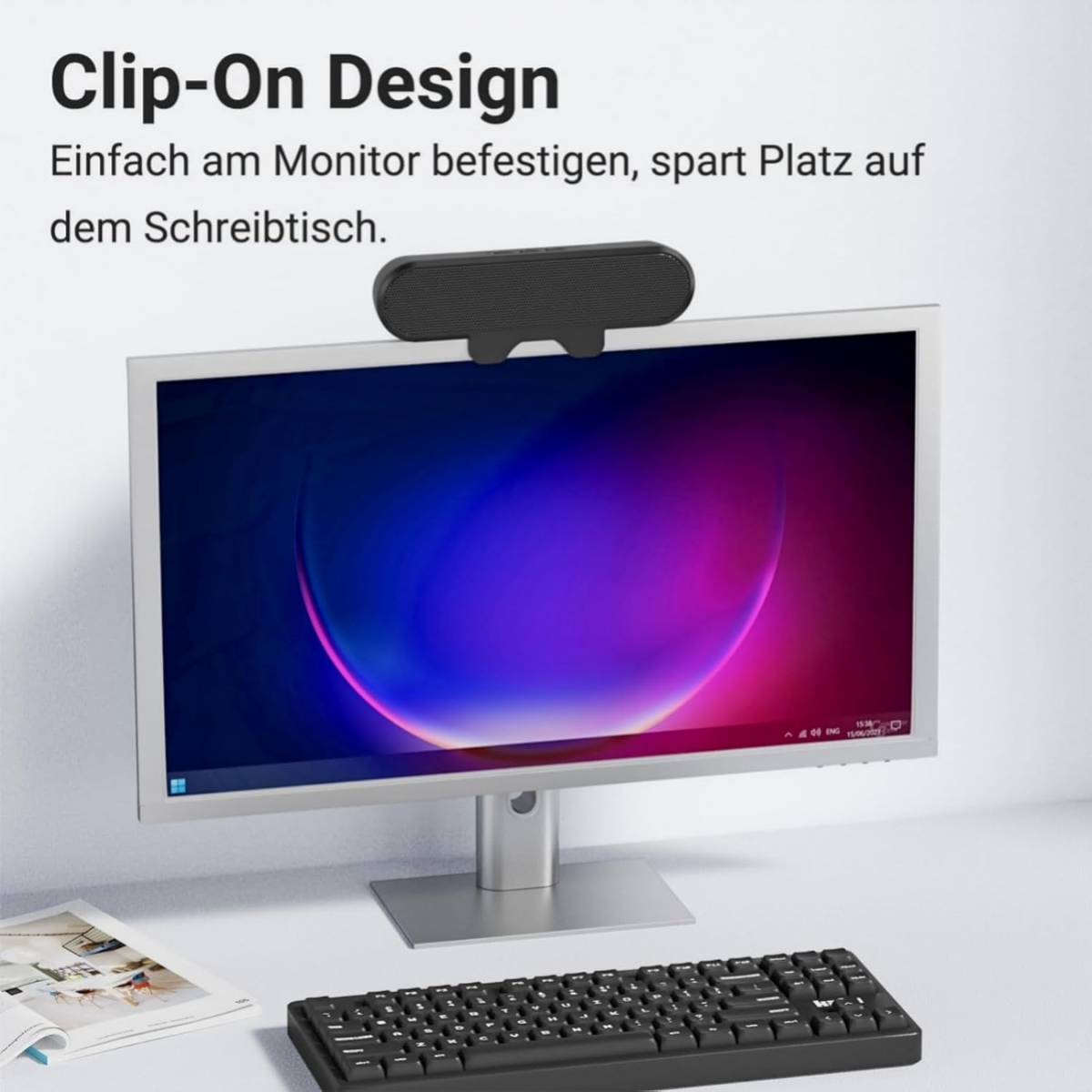Ein schwarzer Lautsprecher sitzt auf einem Monitor über einer Tastatur.