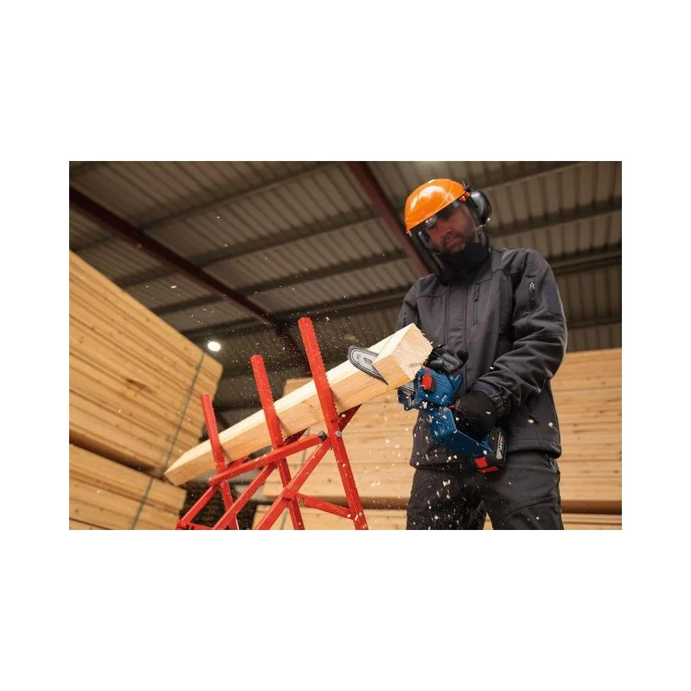 Mann in Schutzkleidung sägt Holz auf einem Ständer. Holzstapel im Hintergrund.