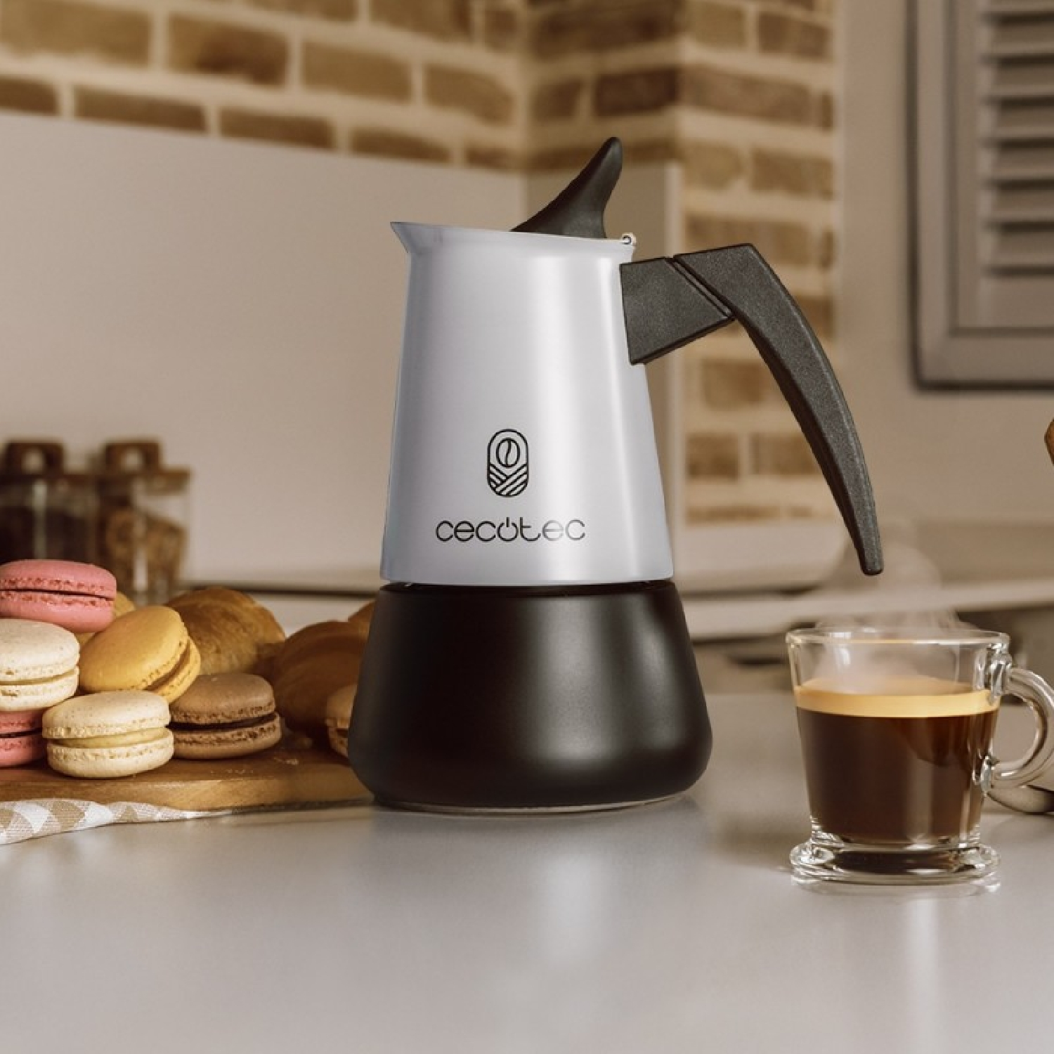 Una caffettiera bianca con manico nero accanto a macaron e caffè.