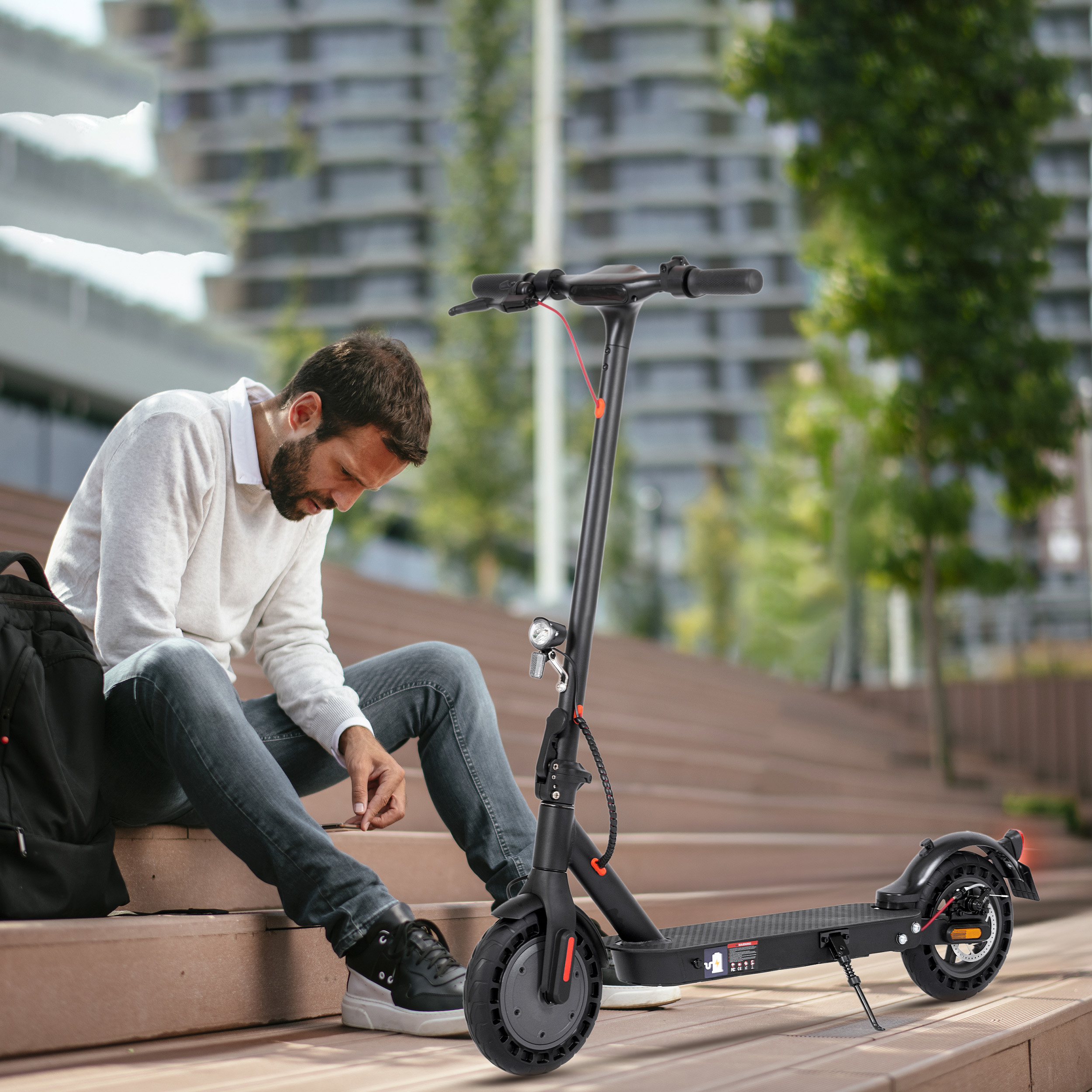 Ein Mann sitzt auf einer Holztreppe neben einem E-Scooter.