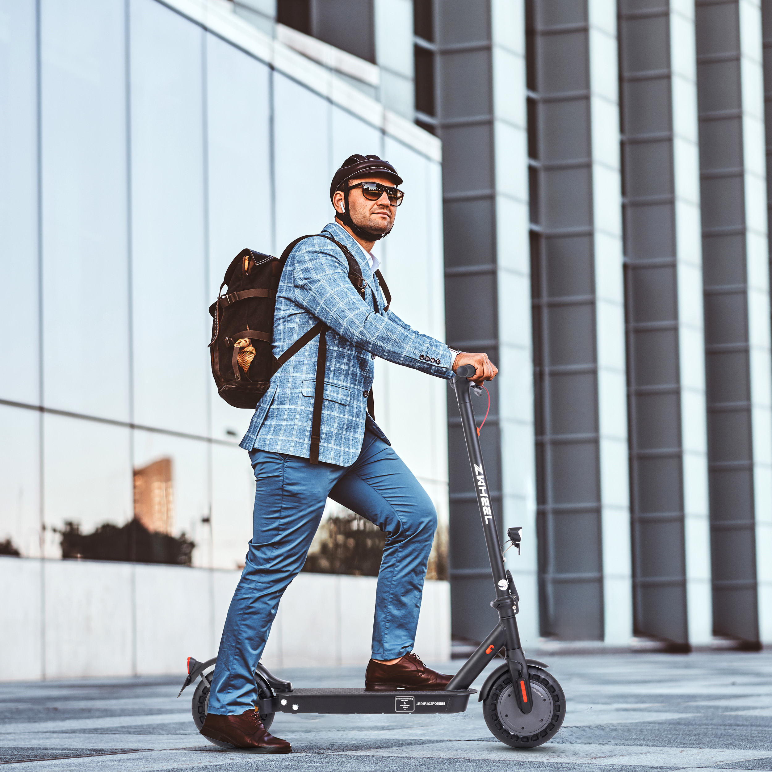 Mann in blauem Karo-Sakko fährt E-Scooter vor modernem Gebäude.