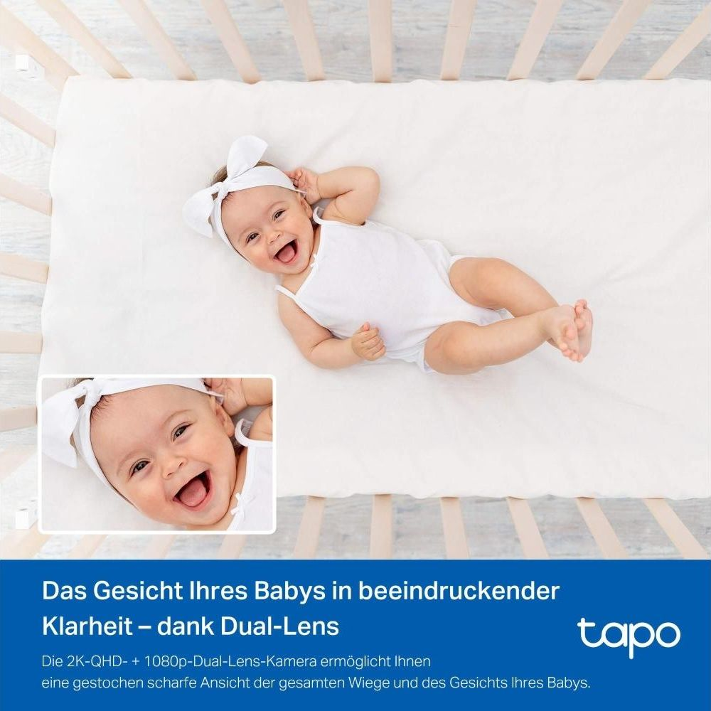 Bambino sorridente in tutina bianca nella culla, primo piano del viso.