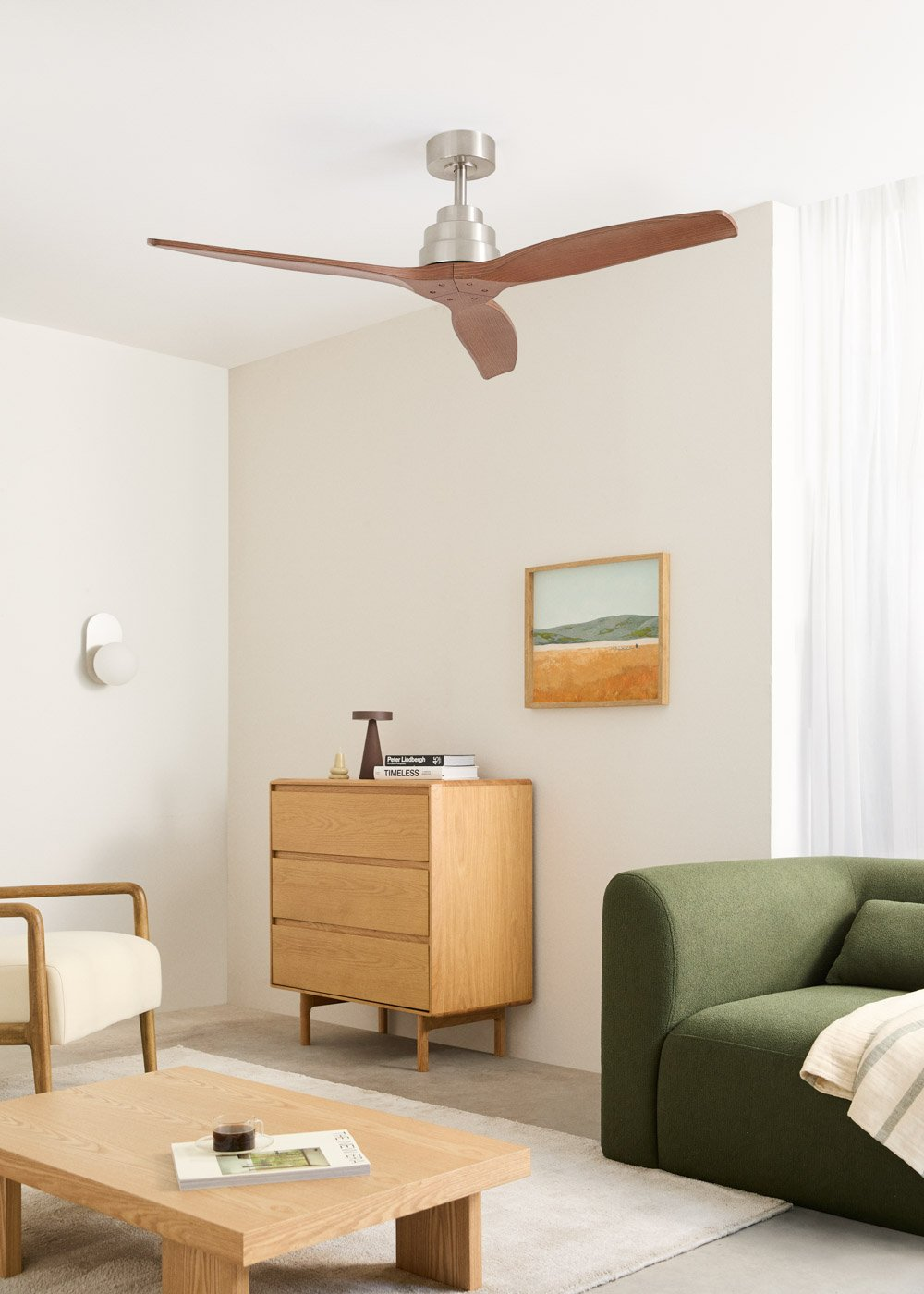 Una sala de estar con cómoda de madera, ventilador de techo, sillón y sofá.