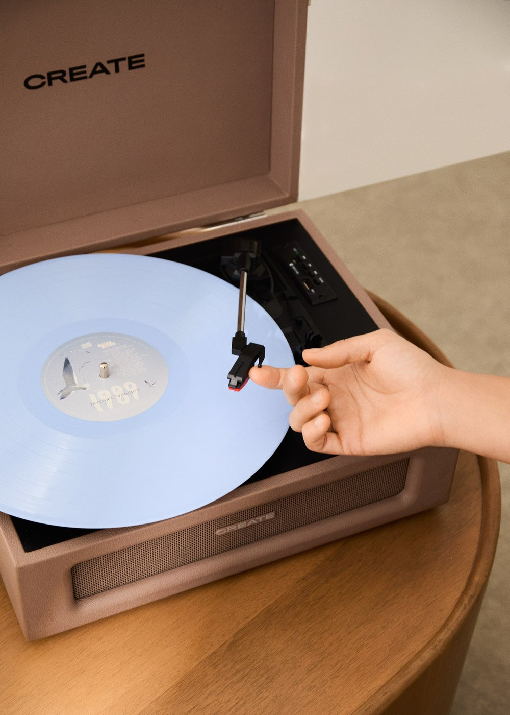 Un dedo toca la aguja de un tocadiscos con un disco de vinilo azul claro.