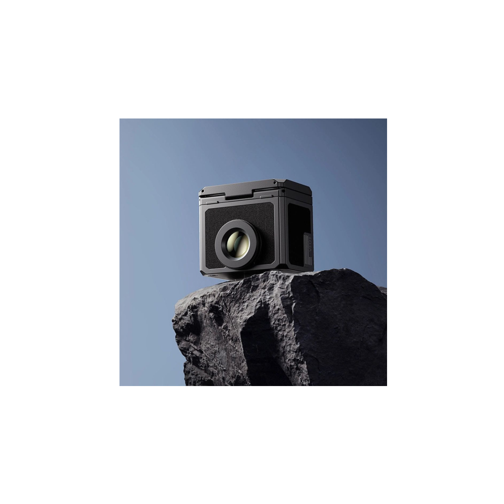 Een zwarte camera op een donkere rots tegen een helderblauwe lucht.