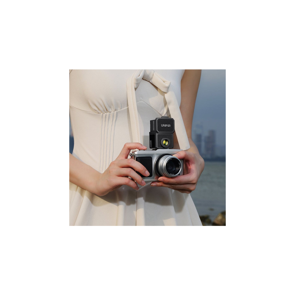 Persoon in witte jurk houdt zilveren camera met opzetstuk vast.