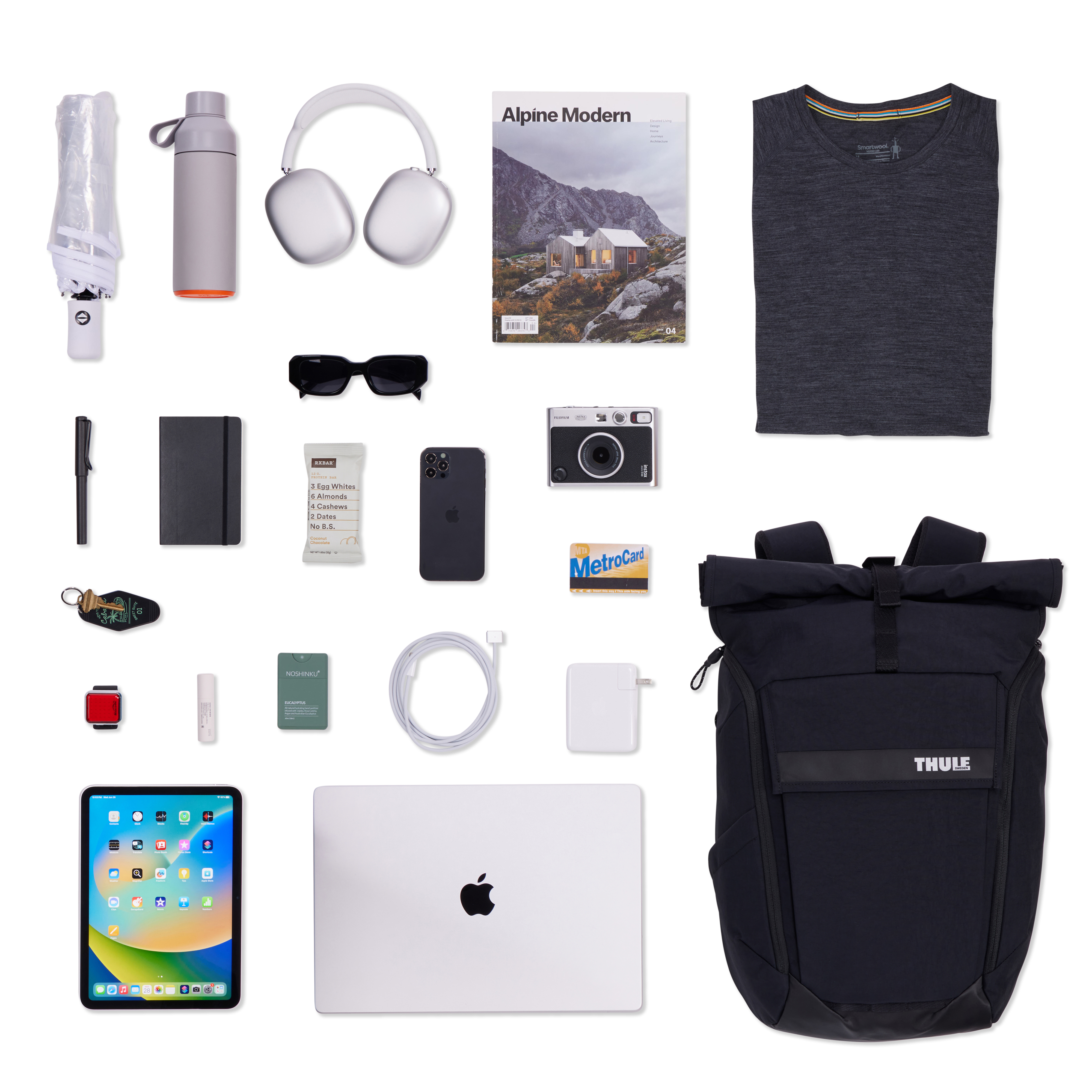 Grauer Rucksack mit Zubehör: Kopfhörer, Buch, Kleidung, Flasche, Kamera, Tech.