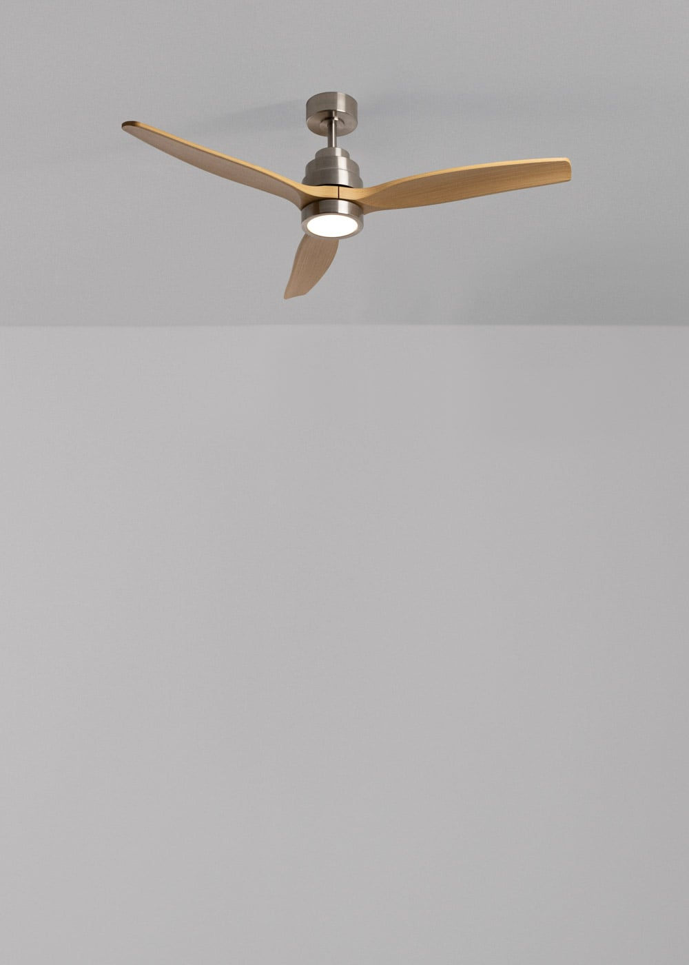 Un ventilador de techo moderno con tres aspas de madera y luz integrada.