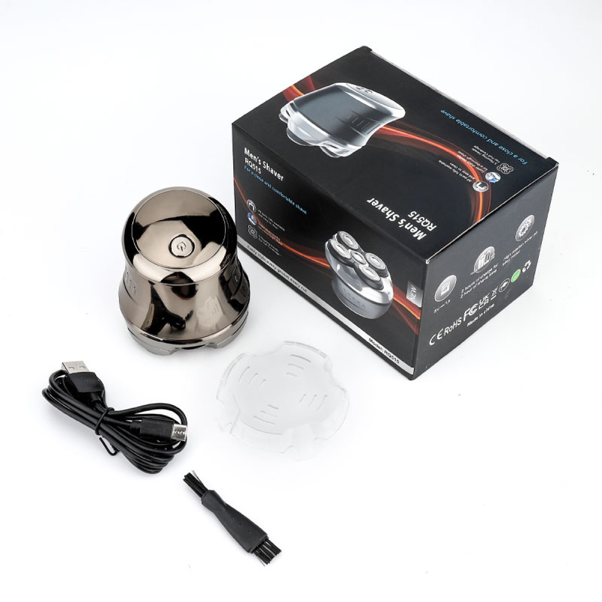 Un rasoio elettrico argentato, cavo USB, cappuccio protettivo e spazzolino accanto alla sua scatola.