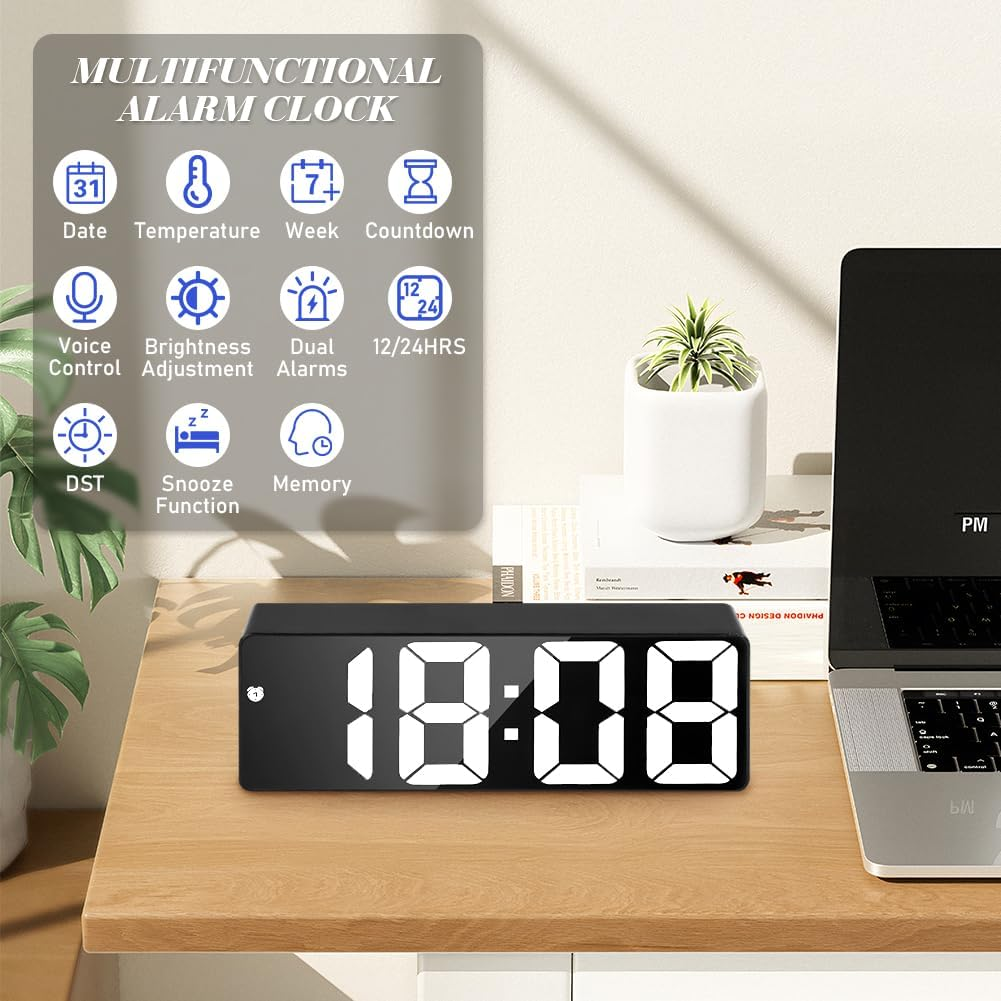 Ein schwarzer Digitalwecker zeigt 18:08 auf einem Holzschreibtisch an, daneben ein Laptop und eine Pflanze.