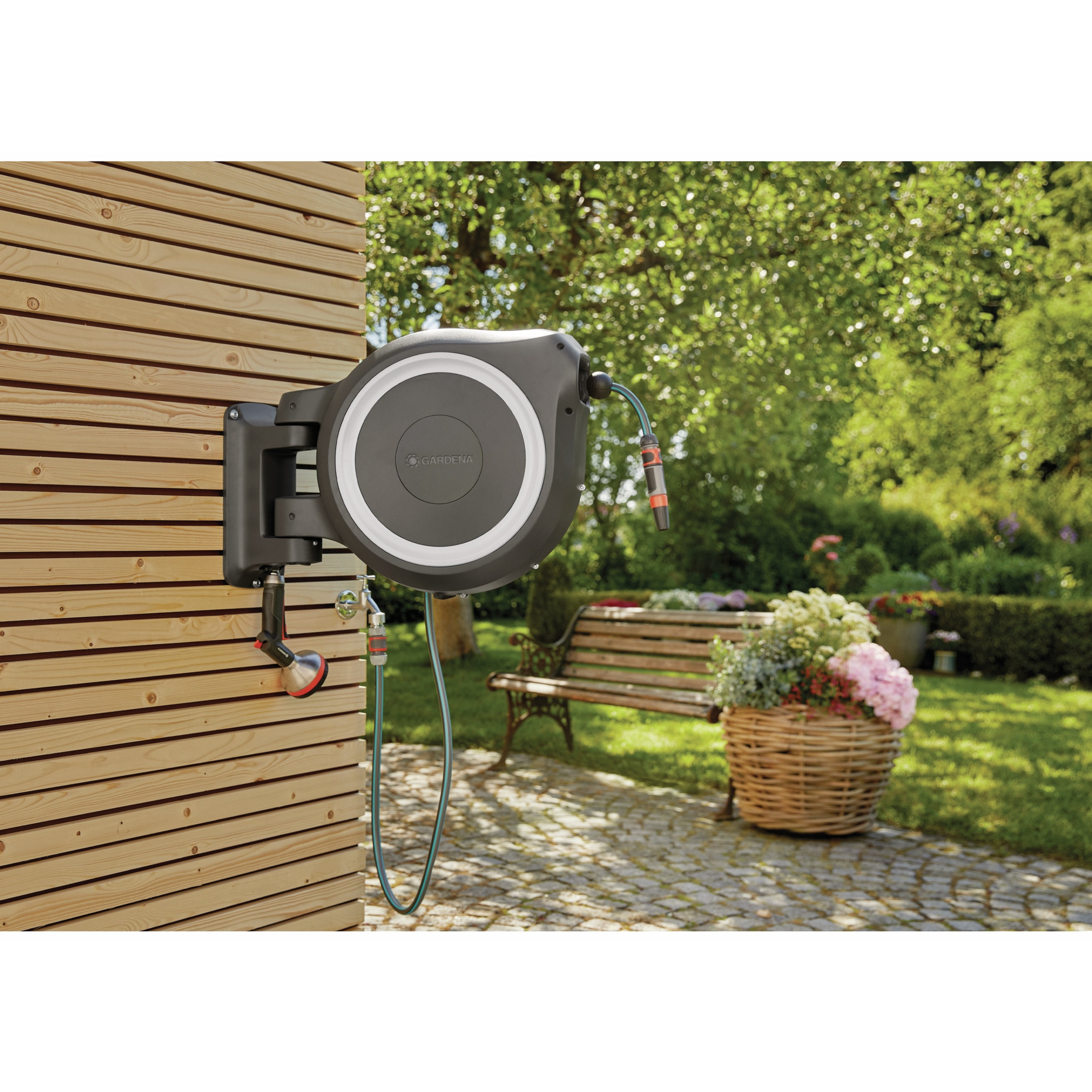 Ein Wand-Schlauchaufroller mit Gartenschlauch und Brause an einer Holzfassade.