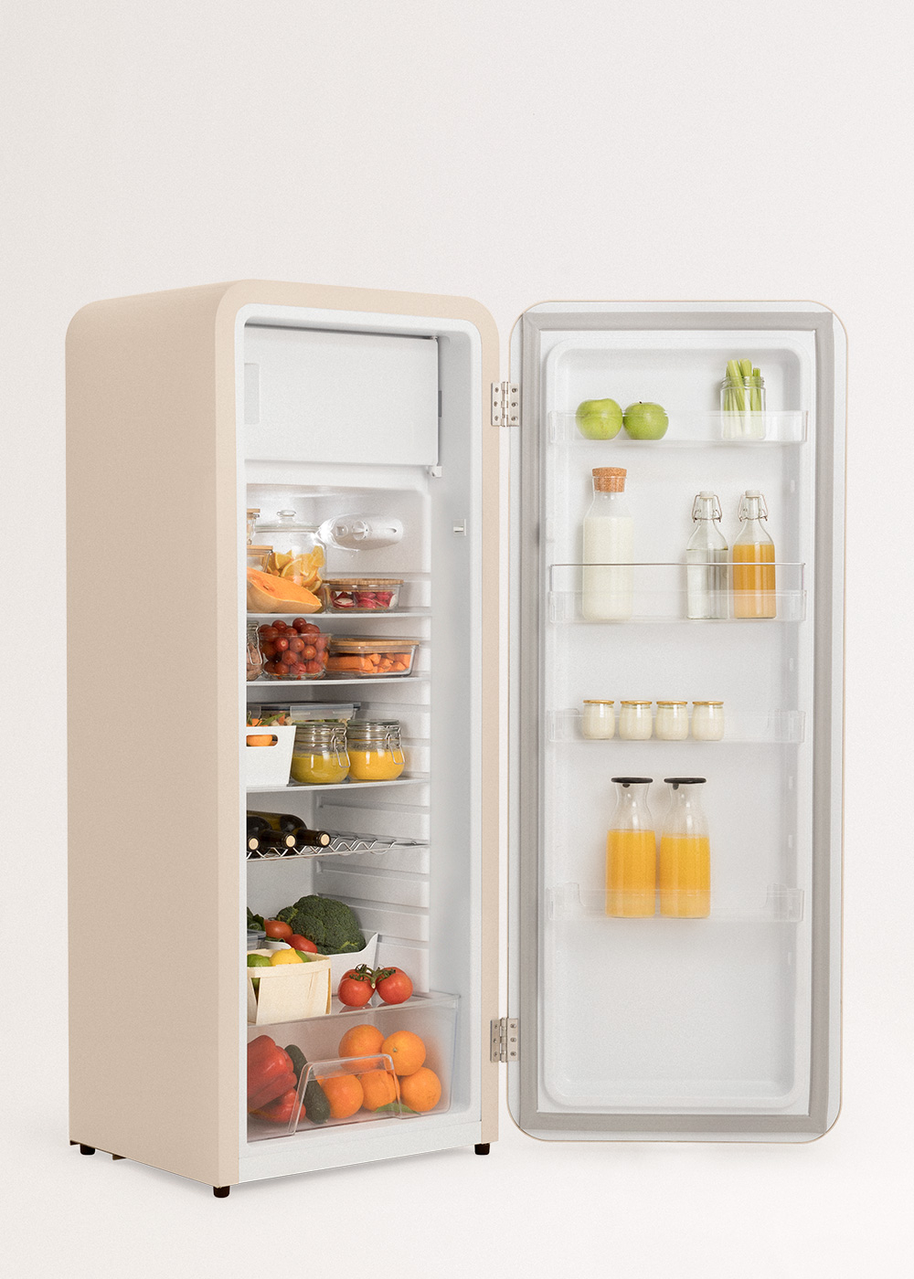 Un refrigerador abierto color crema con alimentos como frutas, verduras y bebidas.