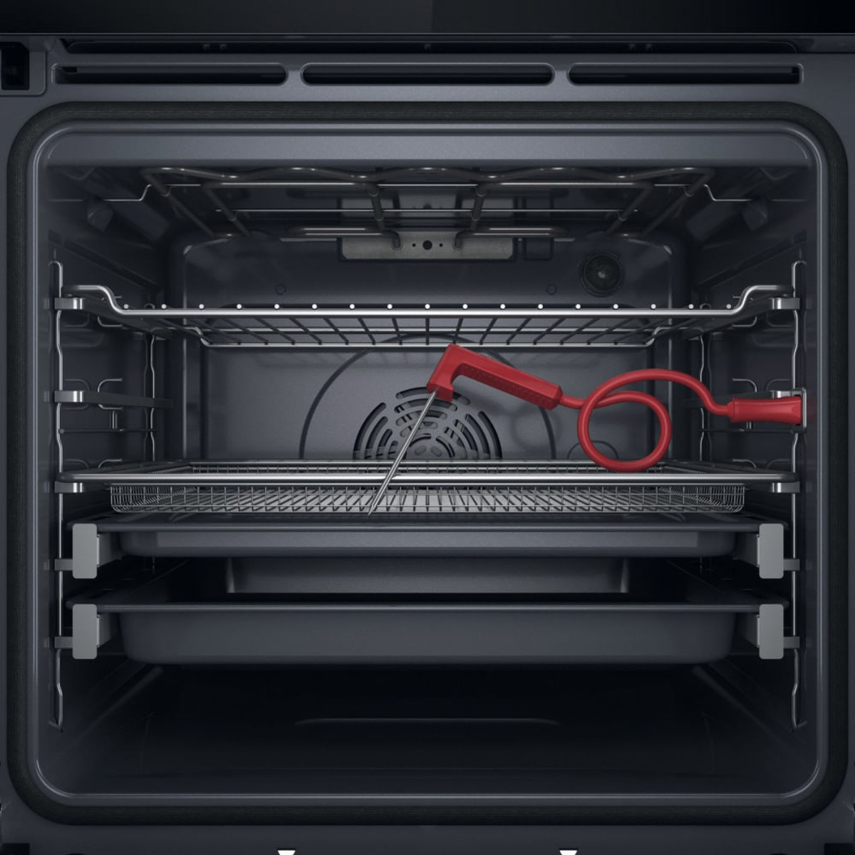 Un termometro per carne rosso con cavo a spirale poggia su una griglia all'interno di un forno aperto.