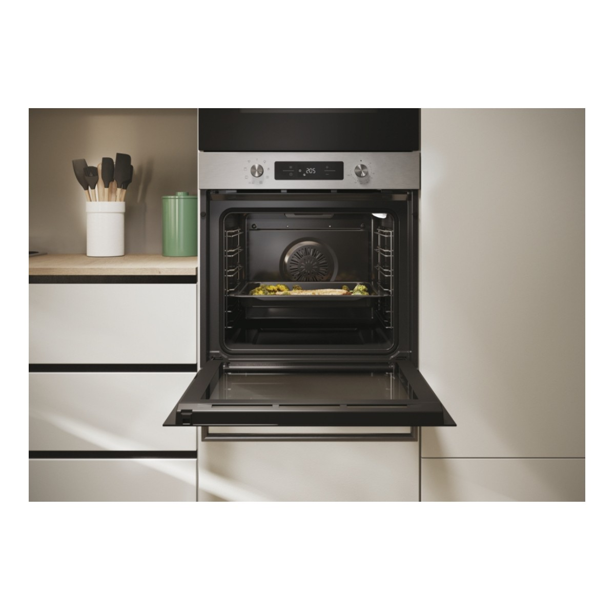 Un forno moderno con la porta aperta, che contiene una teglia con pesce e verdure.