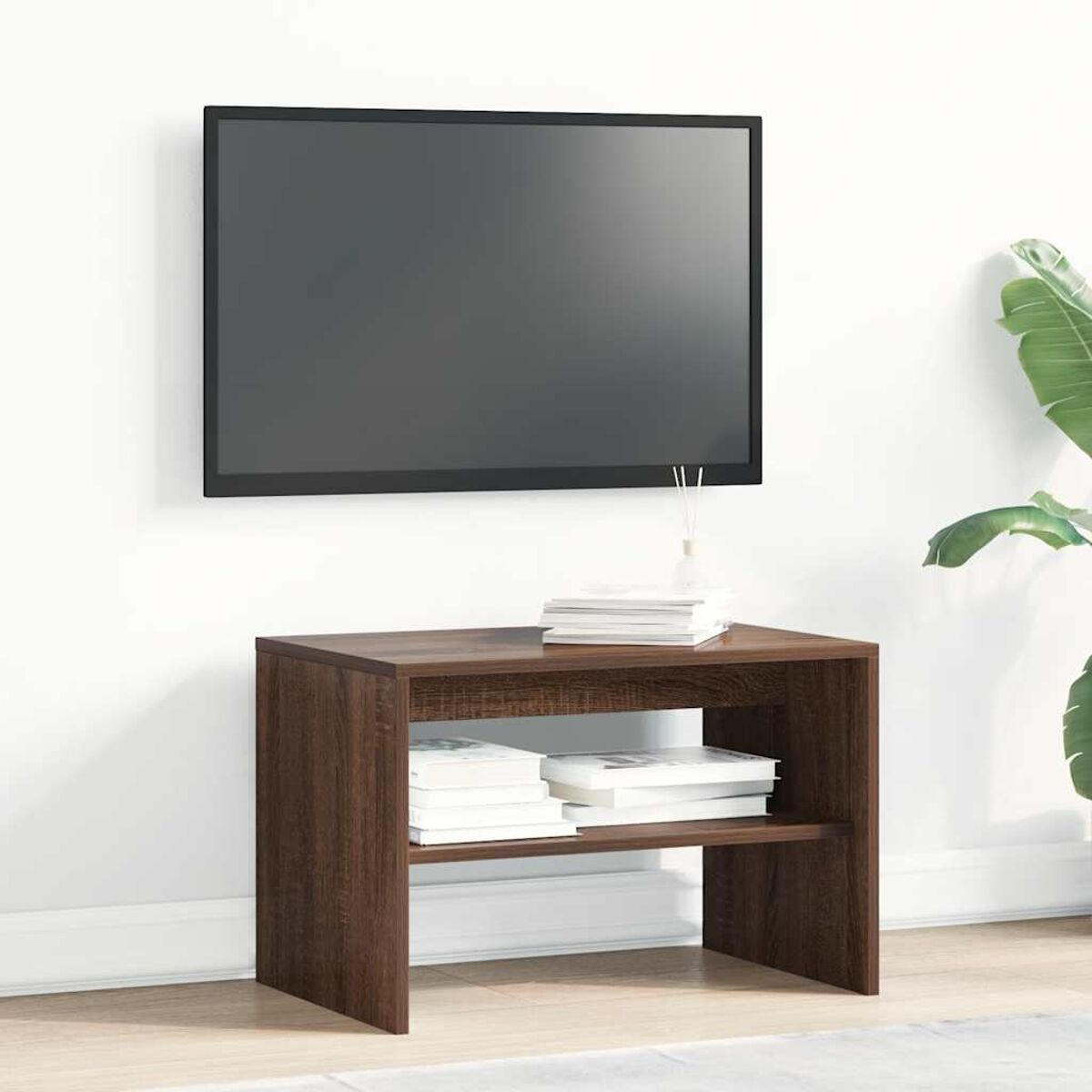 Un mueble de TV de madera oscura con libros y un jarrón bajo un televisor de pared.