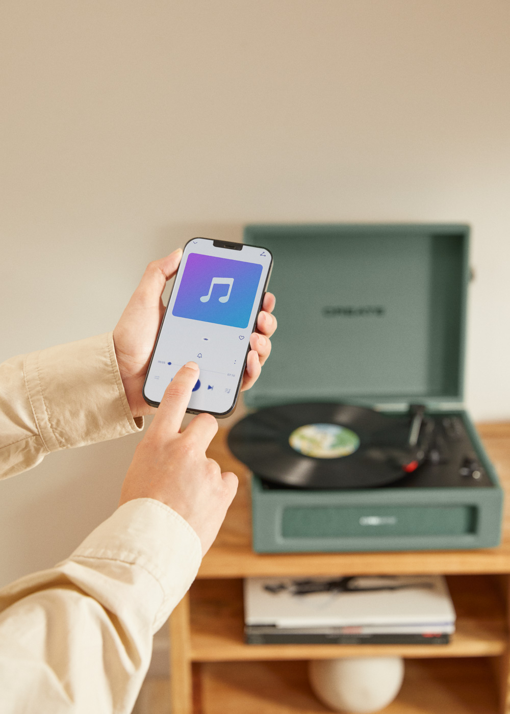 Persona operando smartphone con app de música junto a tocadiscos con disco de vinilo.