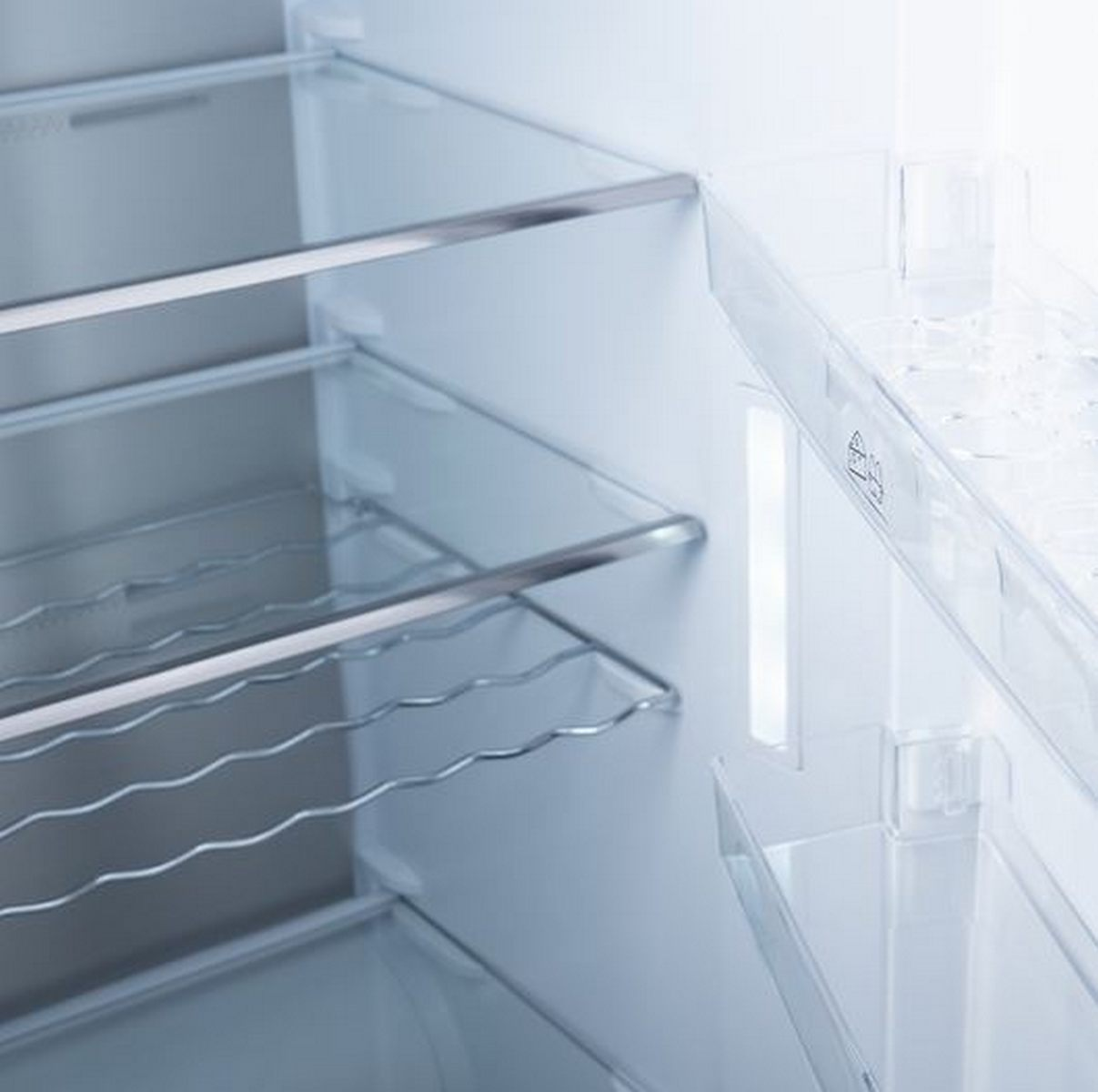 Interior de un refrigerador con estantes de vidrio y un botellero.