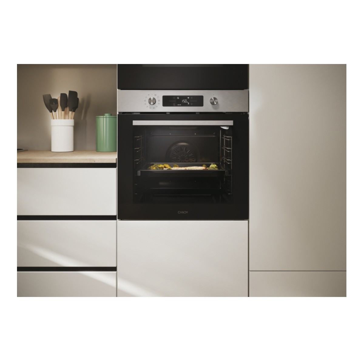 Un forno moderno con cibo all'interno e utensili da cucina accanto.