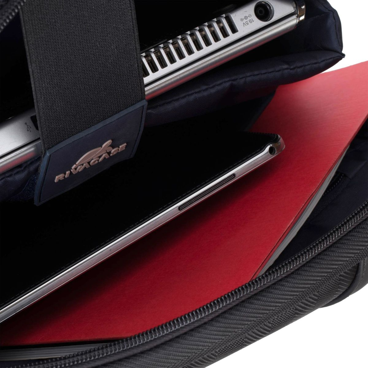 Ein Laptop und ein Tablet befinden sich in einer schwarzen Tasche mit einem roten Notizbuch.