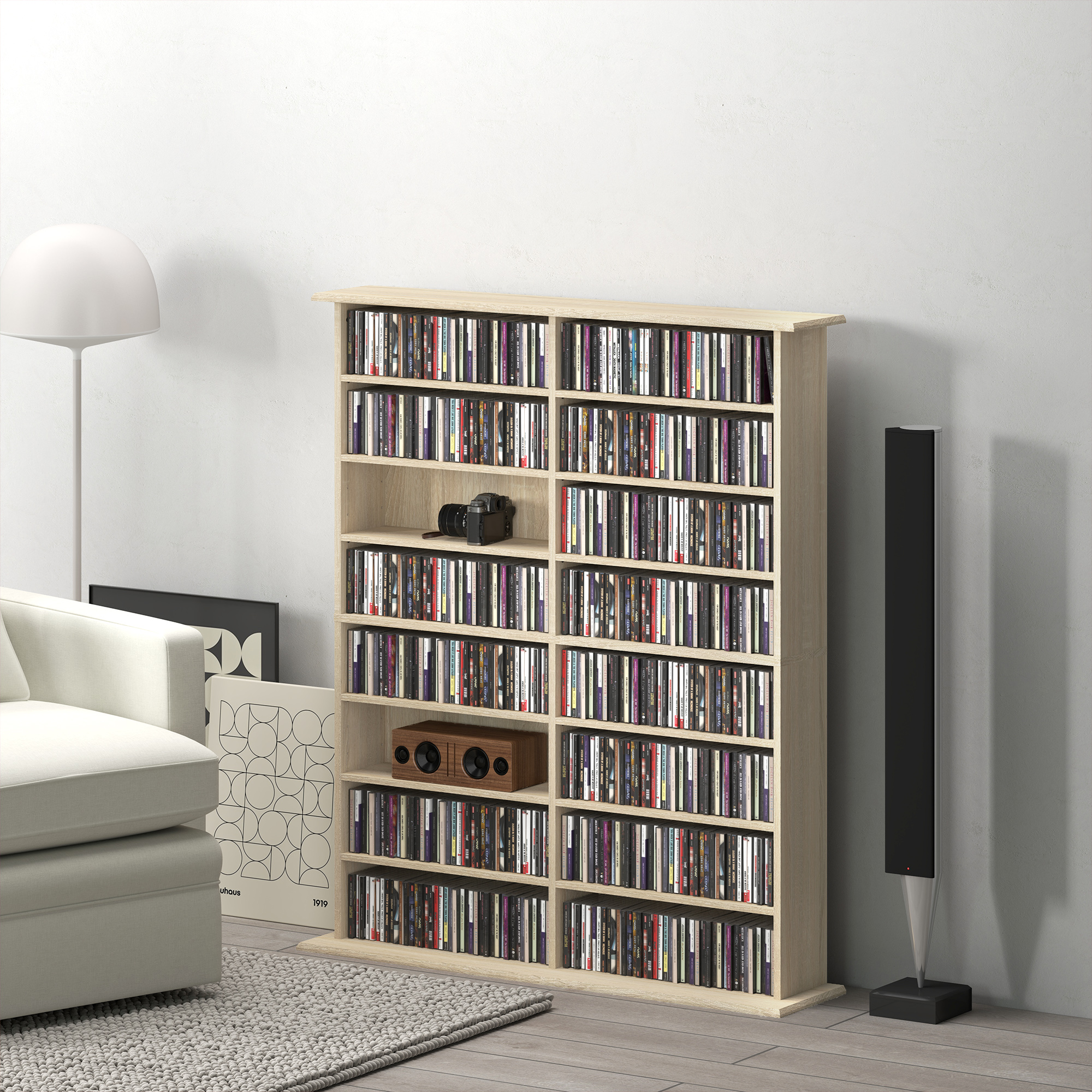 Una libreria in legno chiaro piena di CD, accanto a un divano, lampada e altoparlante.