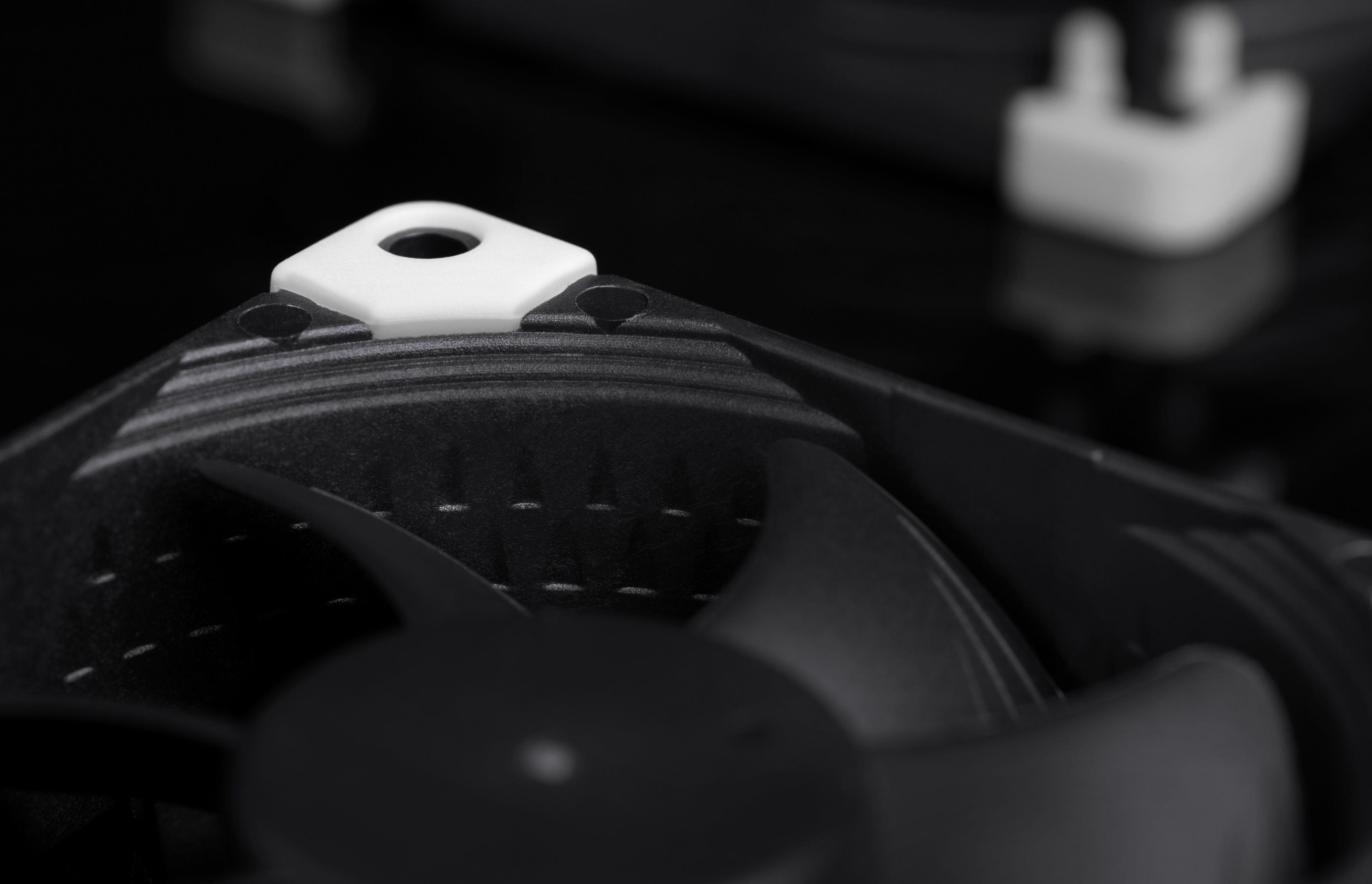 Close-up of a black fan with a white mounting bracket on a black background.