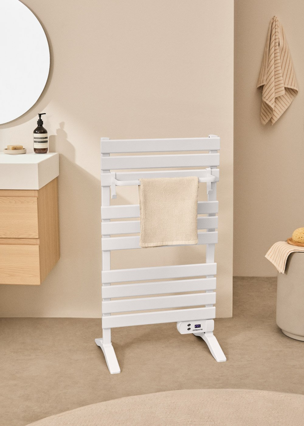 Un toallero eléctrico blanco con una toalla está en un baño junto a un lavabo.