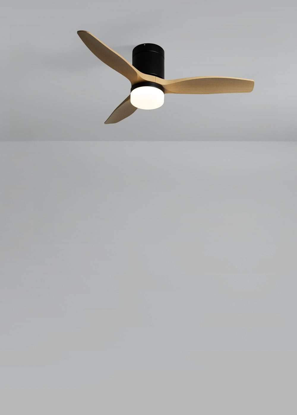 Un ventilador de techo con tres aspas de madera y luz integrada.