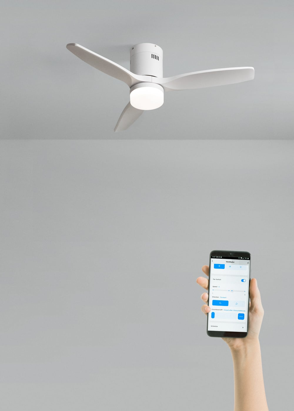 Una lámpara de ventilador de techo blanca de tres aspas controlada por una mano que sostiene un smartphone.