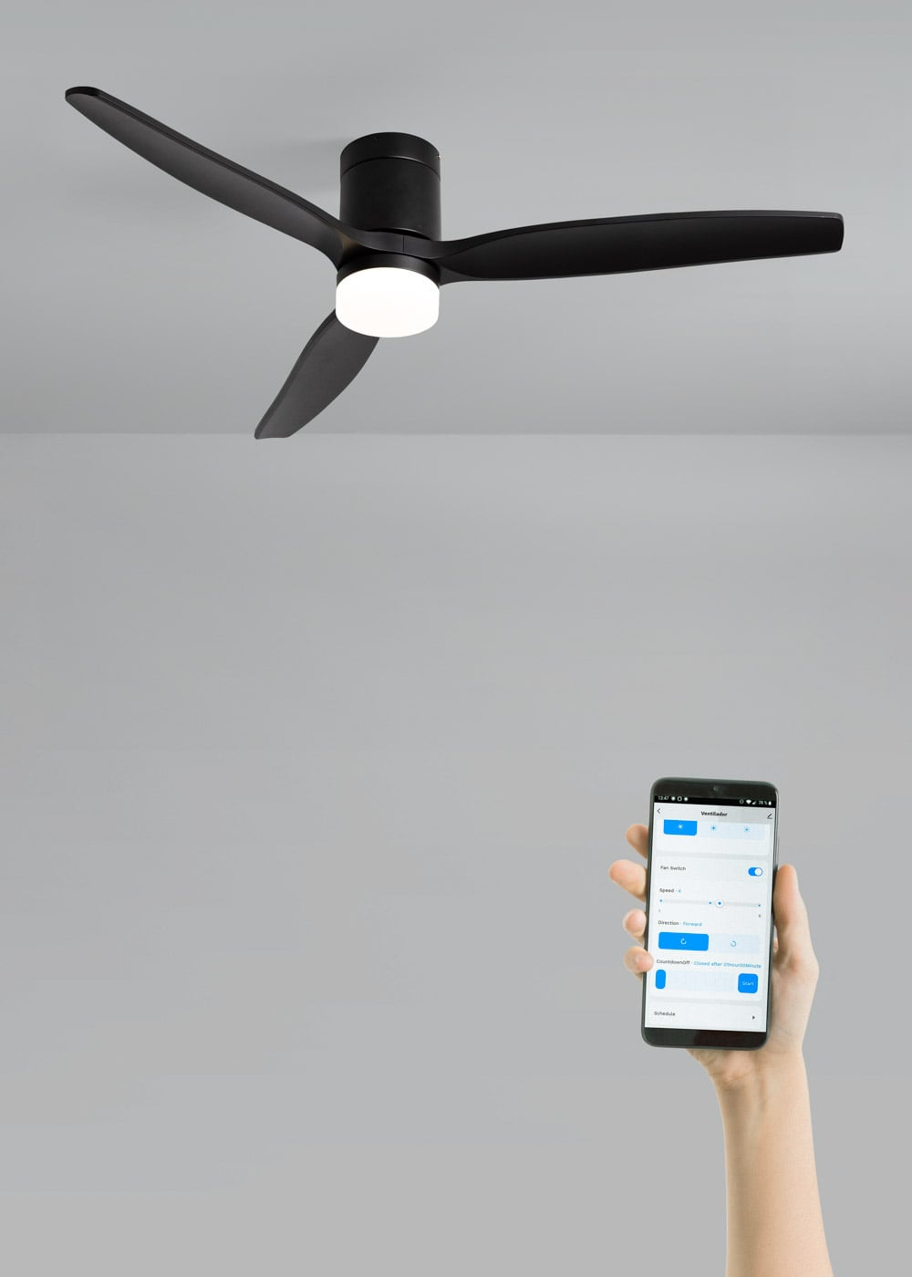 Se muestra un ventilador de techo negro con luz y una mano sosteniendo un teléfono con controles del ventilador.