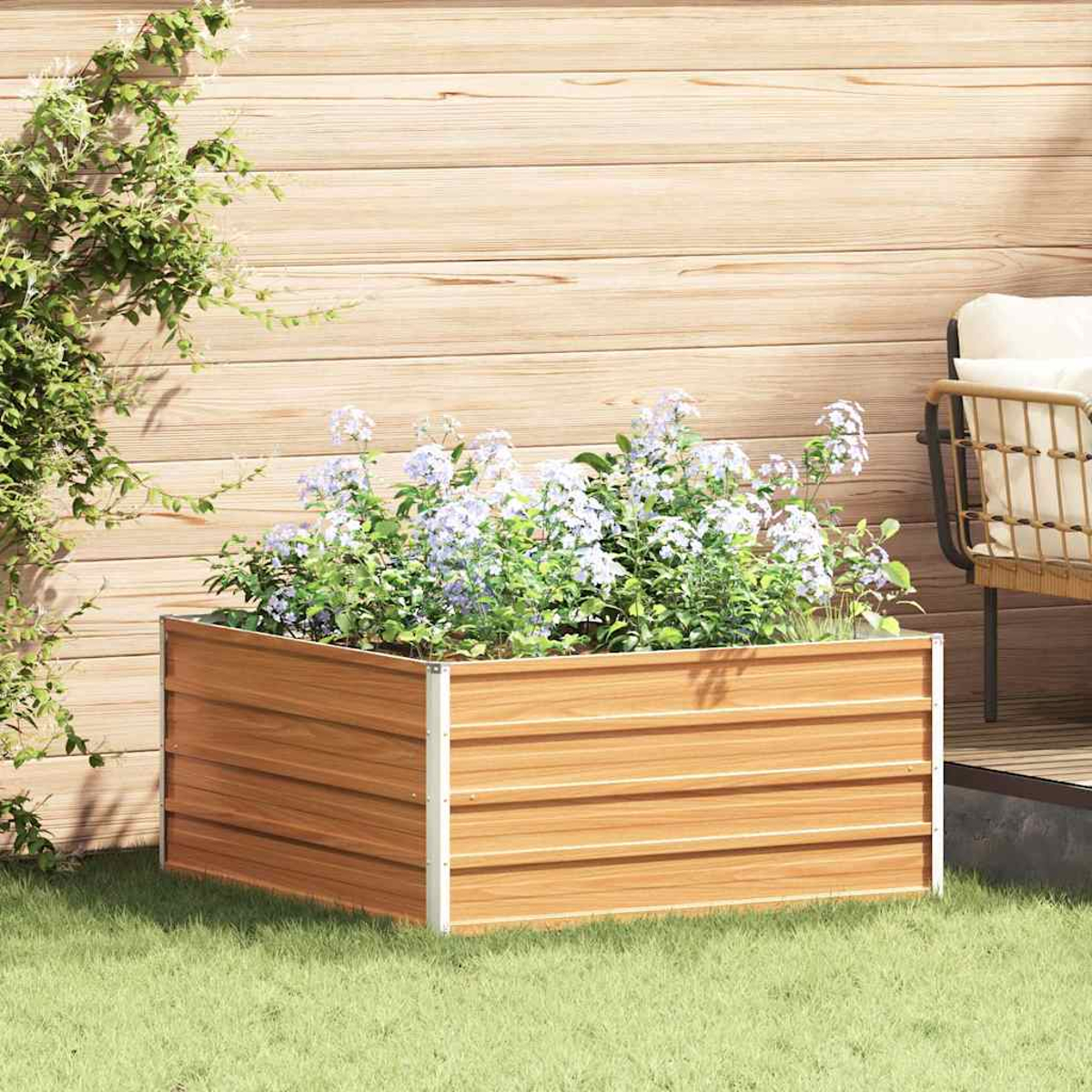 Una fioriera in legno con fiori viola si trova sull'erba verde accanto a un muro di legno.