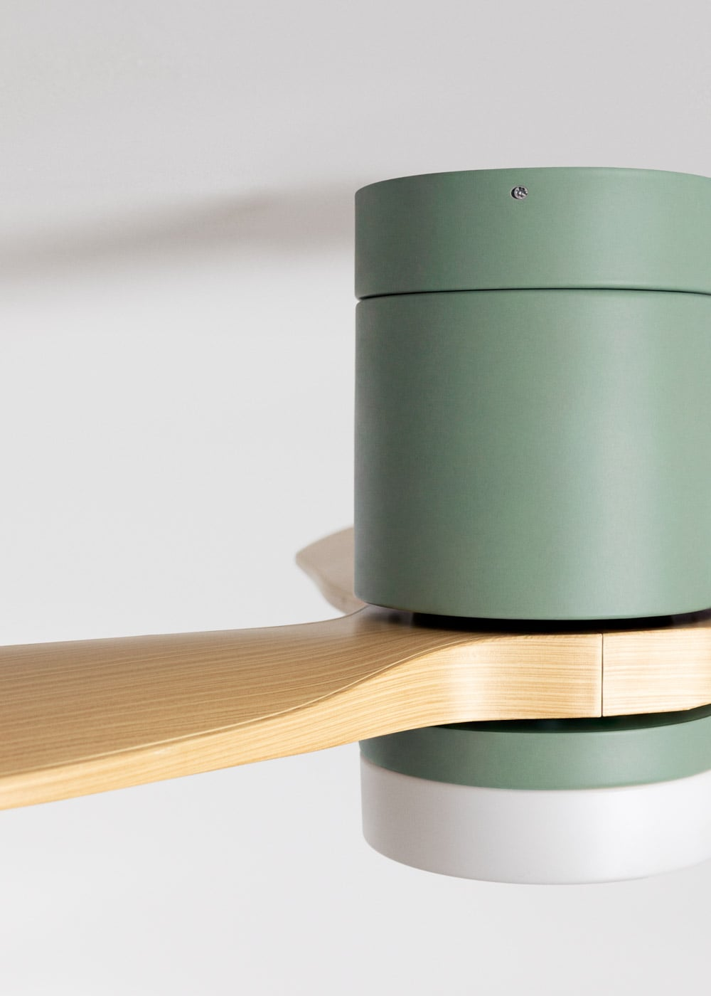 Primer plano de un ventilador de techo moderno con cilindros verdes y blancos y pala de madera.