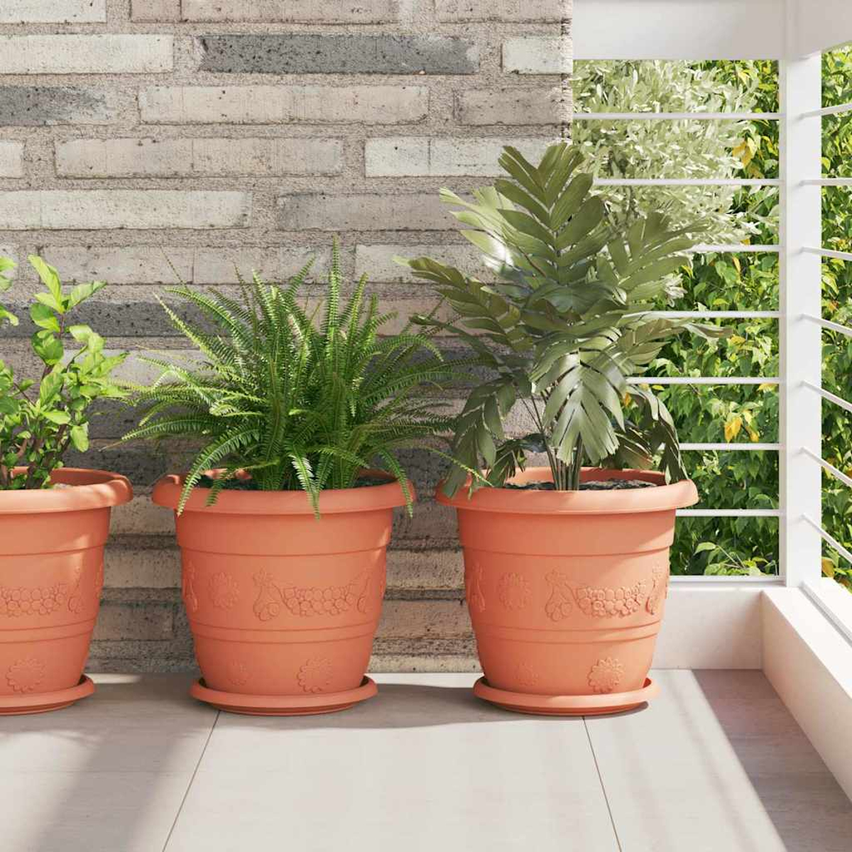 Tre piante in vasi di terracotta su un balcone, di fronte a un muro di mattoni.