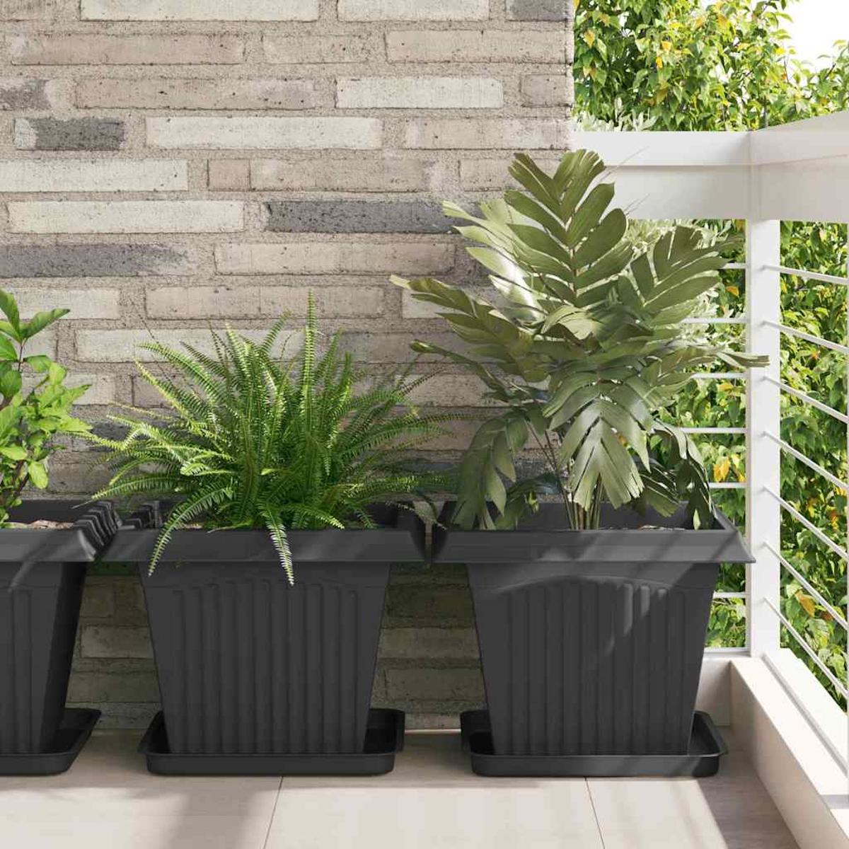 Fioriere scure con felci e piante frondose su un balcone vicino a un muro di mattoni.