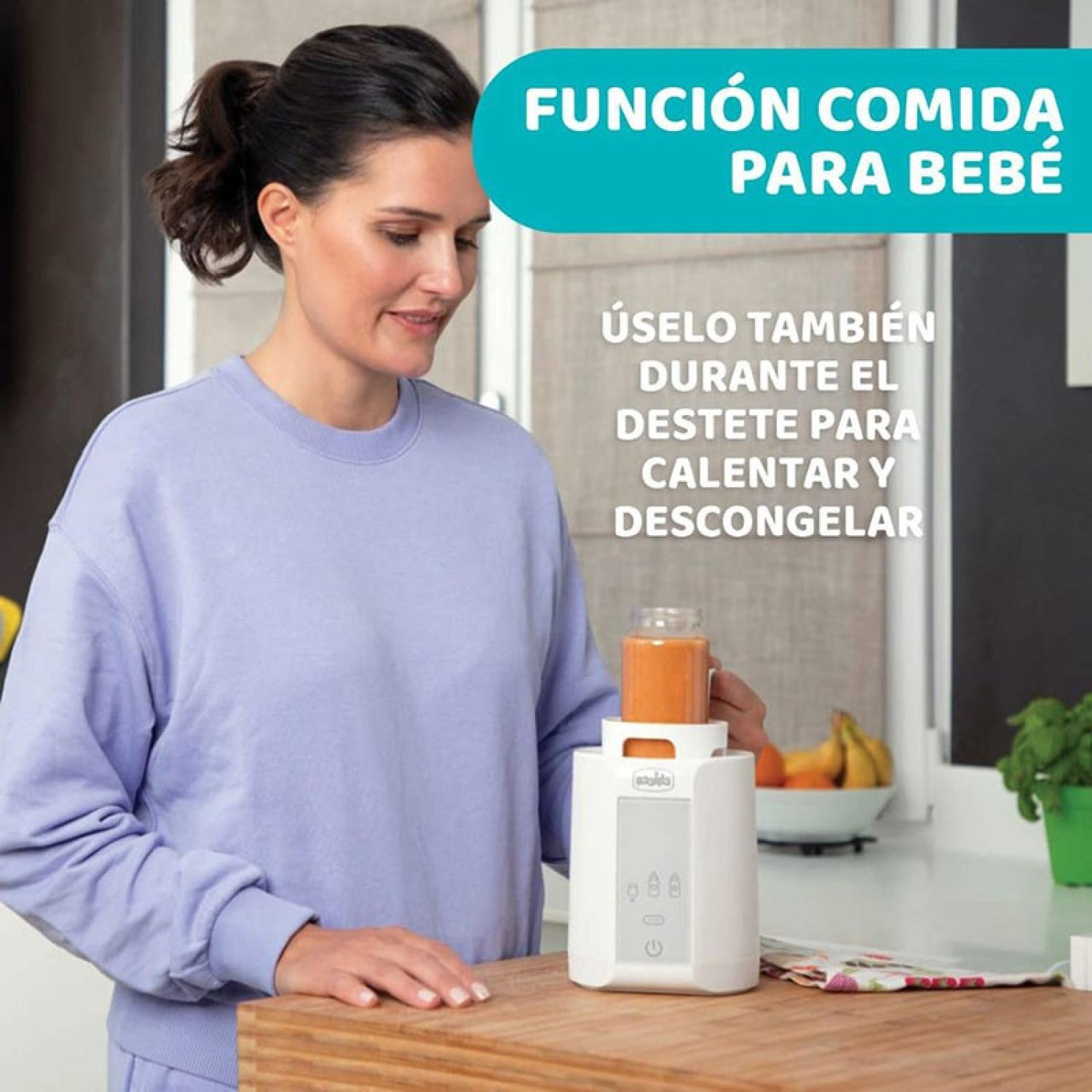 Eine Frau mit Dutt im lila Pullover hält ein Glas Babynahrung über einem weißen Gerät.