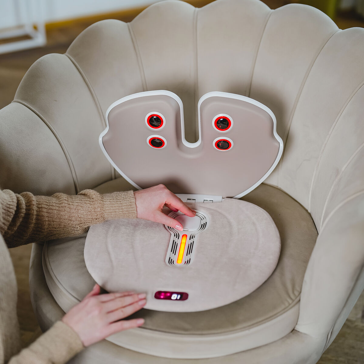 Una persona opera un masajeador en un sillón. Se ven luces rojas.