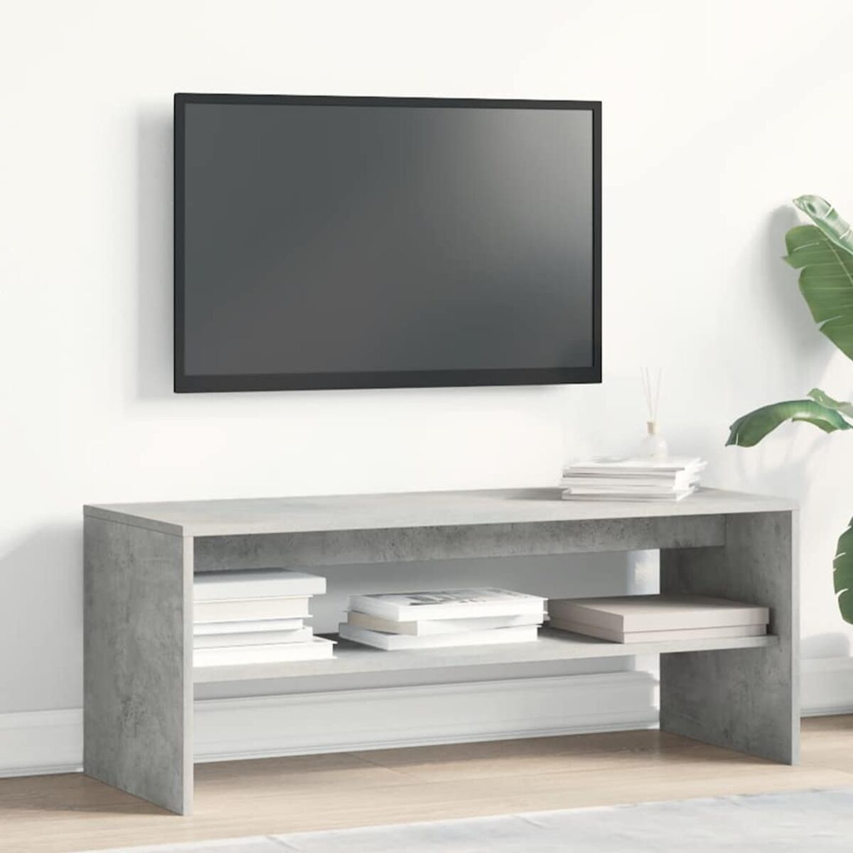 Un mueble de TV gris con libros, un televisor en la pared al lado.