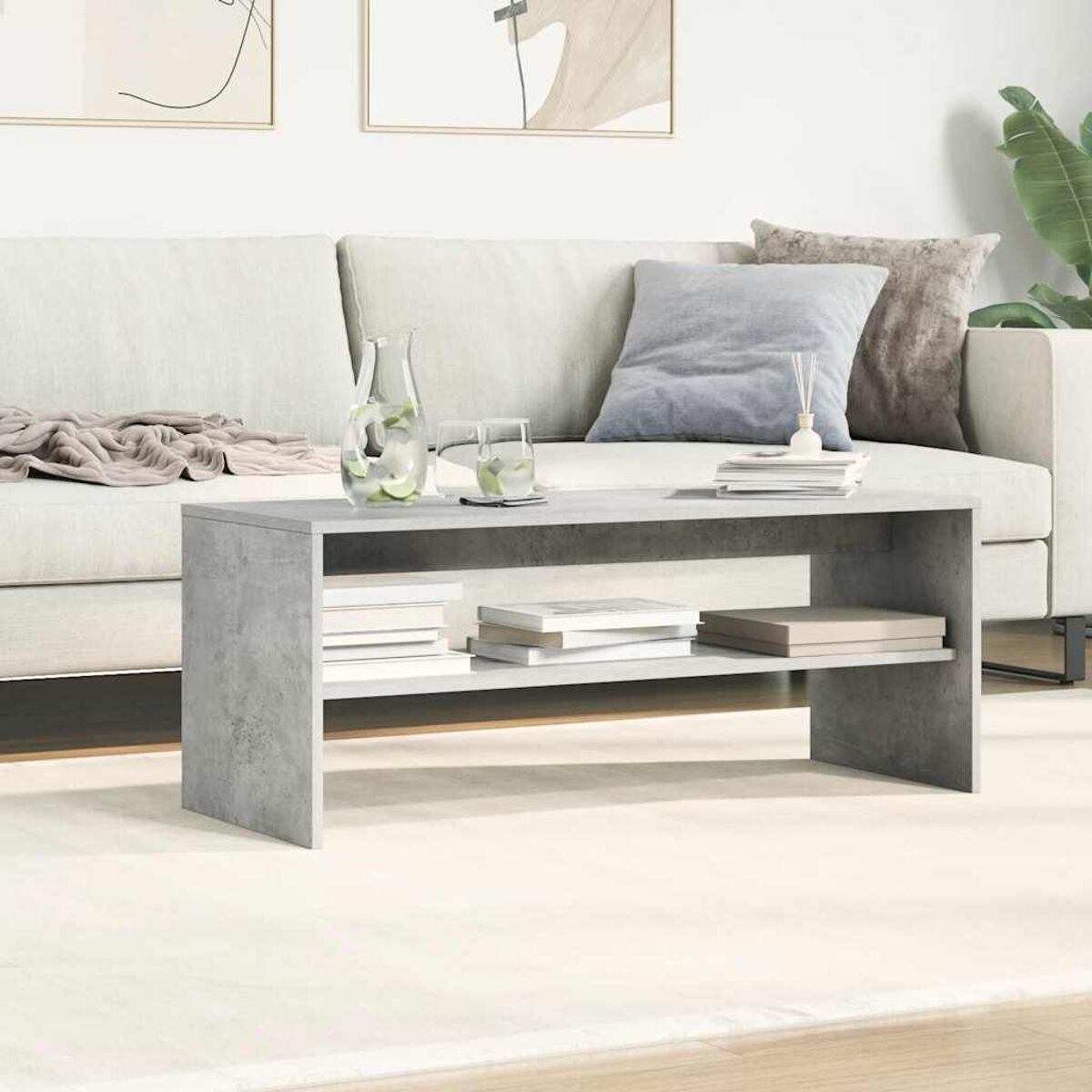 Mesa de centro gris de dos niveles con libros y decoración.