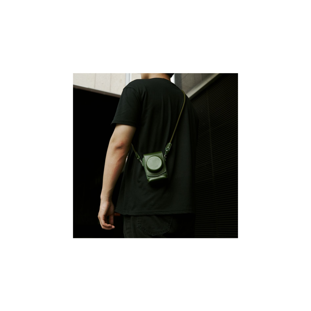 Een man in zwart t-shirt draagt een groene cameratas om zijn nek.