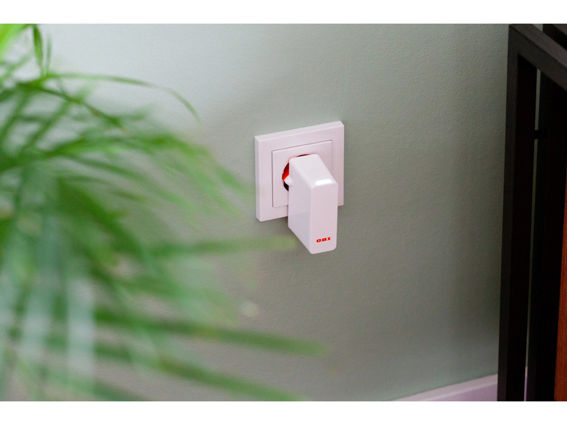 Ein wei''er Stecker mit rotem Logo ist in eine wei''e Steckdose gesteckt.