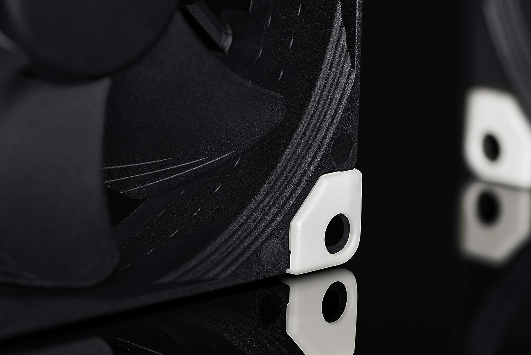 Close-up of a black fan with white corners on a black background.