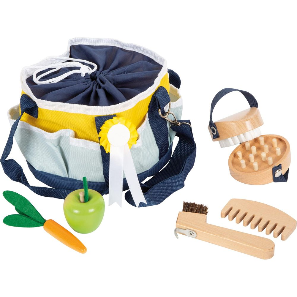 Eine Spielzeugtasche mit Bürsten, Kamm, Apfel und Karotte.