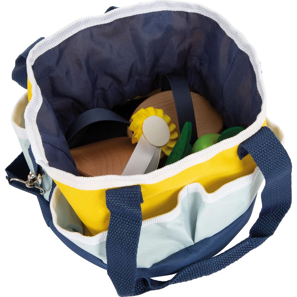 Offene bunte Stofftasche mit Spielzeug wie ein Holzpferd und eine Rosette.