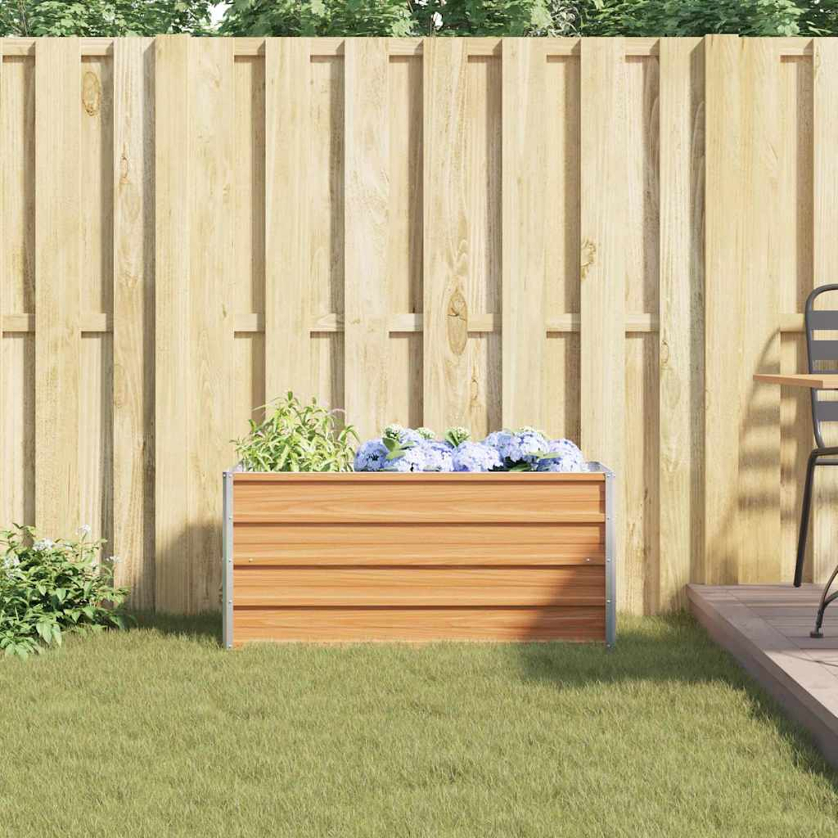 Un'aiuola rialzata in legno con fiori blu davanti a una recinzione di legno.